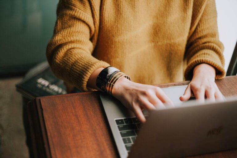 female in yellow sweater with bracelets on the computer