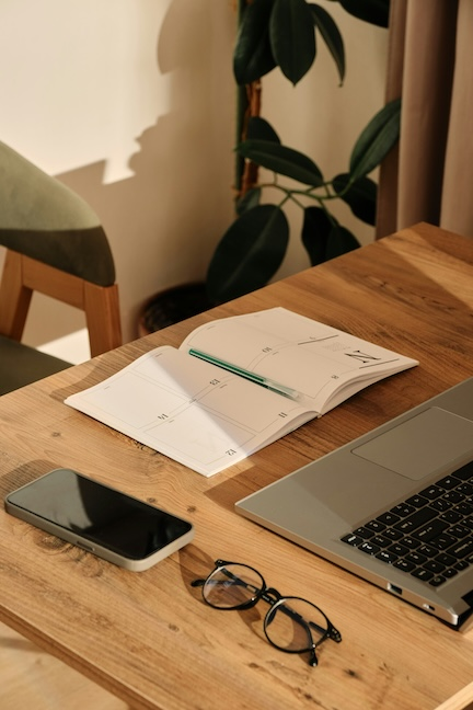 laptop, phone, glasses and calendar on a desk