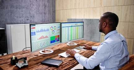 Person analyzing data on dual monitors.